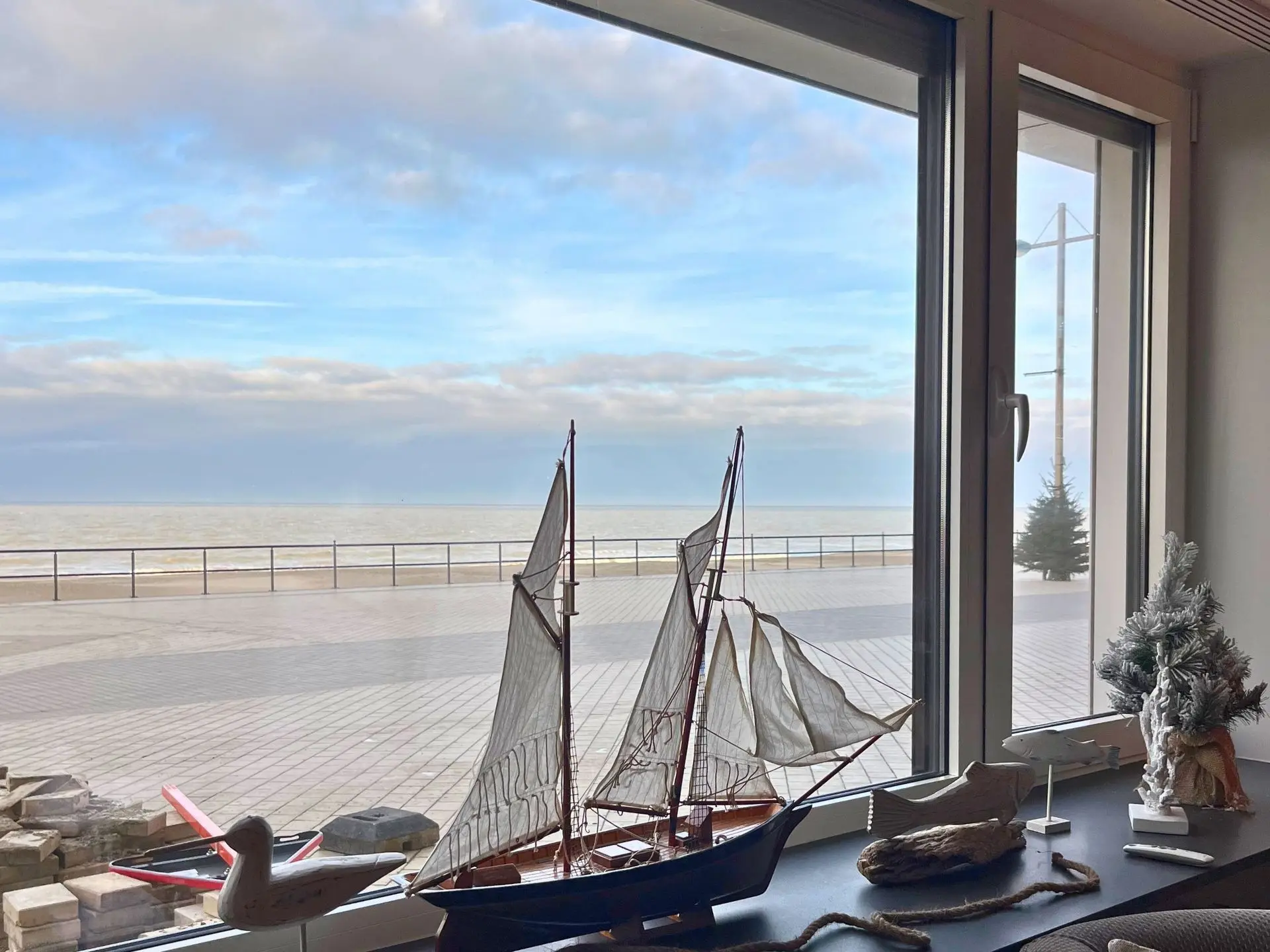 Fenêtre du Seaside qui donne sur la mer avec un bateau en maquette sur le bord de fenêtre